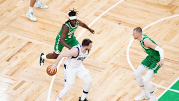 Jun 17, 2024; Boston, Massachusetts, USA; Dallas Mavericks guard Luka Doncic (77) controls the ball against Boston Celtics guard Jrue Holiday (4) and center Kristaps Porzingis (8) in the first quarter during game five of the 2024 NBA Finals at TD Garden. Mandatory Credit: David Butler II-Imagn Images