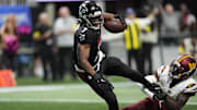 Sep 28, 2025; Atlanta, Georgia, USA; Atlanta Falcons running back Bijan Robinson (7) scores a touchdown against Washington Commanders cornerback Mike Sainristil (0) during the first half at Mercedes-Benz Stadium. Mandatory Credit: Dale Zanine-Imagn Images