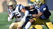Nov 6, 2021; South Bend, Indiana, USA; Navy Midshipmen running back Carlinos Acie (25) is tackled by Notre Dame Fighting Irish safety DJ Brown (2) in the first quarter at Notre Dame Stadium. 