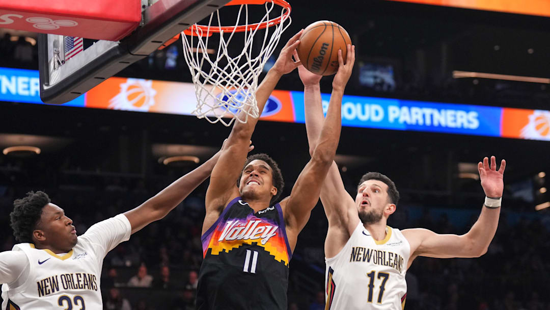Mar 6, 2026; Phoenix, Arizona, USA; Phoenix Suns forward Oso Ighodaro (11) dunks over New Orleans Pelicans center Derik Queen (22) and New Orleans Pelicans forward Karlo Matkovic (17) during the first half at Mortgage Matchup Center. Mandatory Credit: Joe Camporeale-Imagn Images