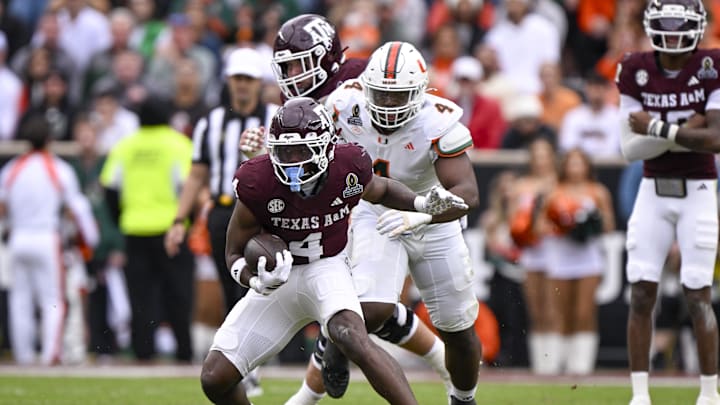Dec 20, 2025; College Station, TX, USA; Texas A&M Aggies running back Rueben Owens II (4) runs with the ball past Miami Hurricanes defensive lineman Rueben Bain Jr. (4) during the game between the Aggies and the Hurricanes at Kyle Field. Mandatory Credit: Jerome Miron-Imagn Images