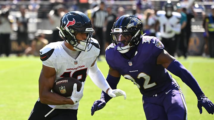 Houston Texans wide receiver Xavier Hutchinson runs for a gain past Baltimore Ravens linebacker Trenton Simpson.