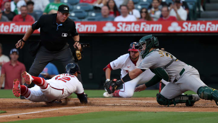 Jul 25, 2024; Anaheim, California, USA;  Los Angeles Angels center fielder Kevin Pillar (12) slides safely into home ahead of  a tag from Oakland Athletics catcher Shea Langeliers (23) during the second inning at Angel Stadium. Mandatory Credit: Kiyoshi Mio-USA TODAY Sports