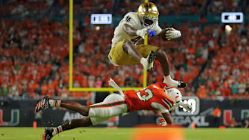 Notre Dame Fighting Irish running back Jeremiyah Love (4) hurdles over Miami Hurricanes defensive back Dylan Day (23) at Hard Rock Stadium. 
