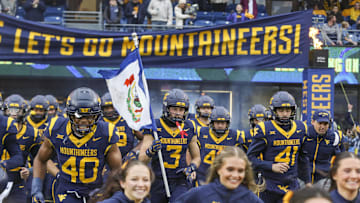 Nov 23, 2024; Morgantown, West Virginia, USA; West Virginia Mountaineers wide receiver Hudson Clement (3) carries the West Virginia state flag as he leads his team onto the field before a game against the UCF Knights at Mountaineer Field at Milan Puskar Stadium. Mandatory Credit: Ben Queen-Imagn Images