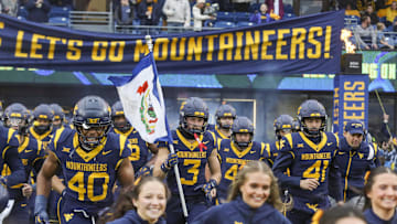 Nov 23, 2024; Morgantown, West Virginia, USA; West Virginia Mountaineers wide receiver Hudson Clement (3) carries the West Virginia state flag as he leads his team onto the field before a game against the UCF Knights at Mountaineer Field at Milan Puskar Stadium. Mandatory Credit: Ben Queen-Imagn Images