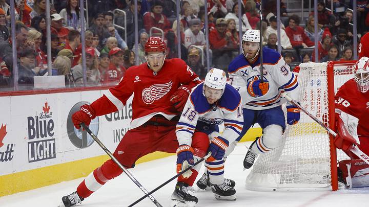Oct 27, 2024; Detroit, Michigan, USA; Detroit Red Wings defenseman Simon Edvinsson (77) fights for control of the puck against Edmonton Oilers left wing Zach Hyman (18) during the third period at Little Caesars Arena. Mandatory Credit: Brian Bradshaw Sevald-Imagn Images