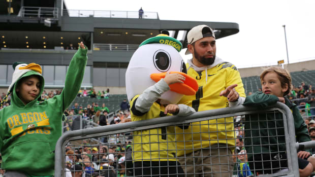 A young Oregon fan dressed as a Duck tries to get the official Oregon Duck’s attention from the stands before the Oregon Spri