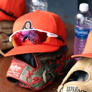 Mar 11, 2024; Tampa, Florida, USA;  A detailed view of Baltimore Orioles baseball hats and gloves in the dugout during the first inning against the New York Yankees at George M. Steinbrenner Field. Mandatory Credit: Kim Klement Neitzel-Imagn Images