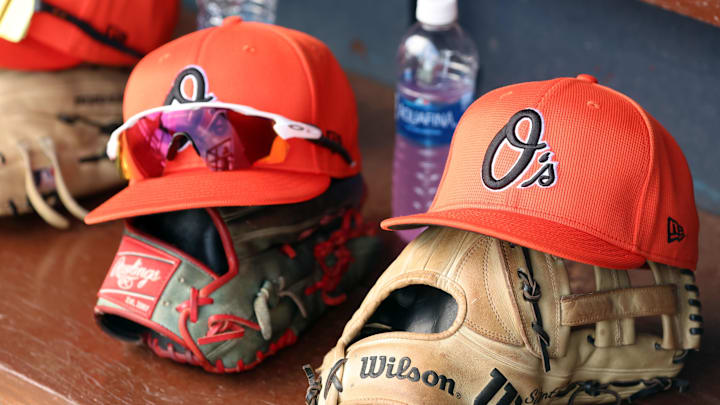 Mar 11, 2024; Tampa, Florida, USA;  A detailed view of Baltimore Orioles baseball hats and gloves in the dugout during the first inning against the New York Yankees at George M. Steinbrenner Field. 