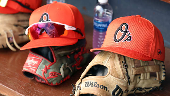 Mar 11, 2024; Tampa, Florida, USA;  A detailed view of Baltimore Orioles baseball hats and gloves in the dugout during the first inning against the New York Yankees at George M. Steinbrenner Field. 