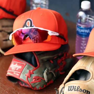 Mar 11, 2024; Tampa, Florida, USA;  A detailed view of Baltimore Orioles baseball hats and gloves in the dugout during the first inning against the New York Yankees at George M. Steinbrenner Field.