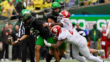 Oct 11, 2025; Eugene, Oregon, USA; Oregon Ducks quarterback Dante Moore (5) tosses the ball to a teammate as he is tackled by Indiana Hoosiers linebacker Aiden Fisher (4) during the second quarter at Autzen Stadium. Mandatory Credit: Troy Wayrynen-Imagn Images