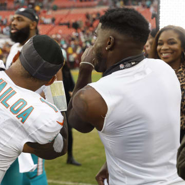 Miami Dolphins quarterback Tua Tagovailoa makes a video with Dolphins wide receiver Tyreek Hill on the field after the victory against the Washington Commanders at FedExField last December.