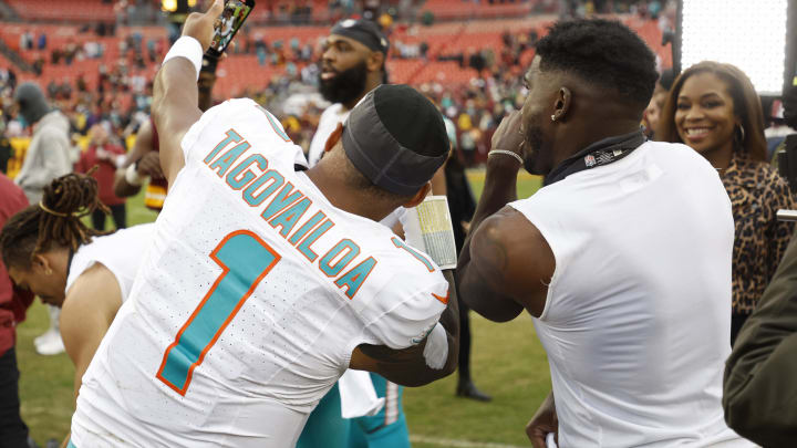 Miami Dolphins quarterback Tua Tagovailoa makes a video with Dolphins wide receiver Tyreek Hill on the field after the victory against the Washington Commanders at FedExField last December.