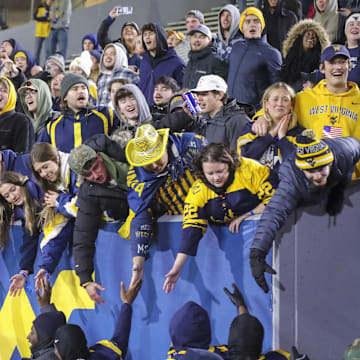 Nov 23, 2024; Morgantown, West Virginia, USA; West Virginia Mountaineers fans celebrate with players after defeating the UCF Knights at Mountaineer Field at Milan Puskar Stadium. Mandatory Credit: Ben Queen-Imagn Images