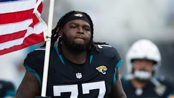 Nov 10, 2024; Jacksonville, Florida, USA;  Jacksonville Jaguars offensive lineman Anton Harrison (77) runs onto the field with the American flag before the. game against the Minnesota Vikings at EverBank Stadium. Mandatory Credit: Jeremy Reper-Imagn Images