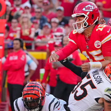 Sep 15, 2024; Kansas City, Missouri, USA; Kansas City Chiefs quarterback Patrick Mahomes (15) is hit by Cincinnati Bengals linebacker Logan Wilson (55) while throwing a pass during the second half at GEHA Field at Arrowhead Stadium. Mandatory Credit: Denny Medley-Imagn Images