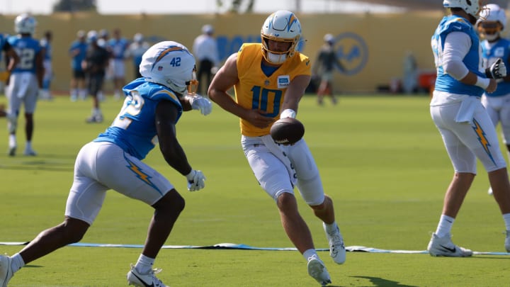 Jul 24, 2024; El Segundo, CA, USA;  Los Angeles Chargers quarterback Justin Herbert (10) hands off to running back Elijah Dotson (42) during the first day of training camp at The Bolt. Mandatory Credit: Kiyoshi Mio-USA TODAY Sports