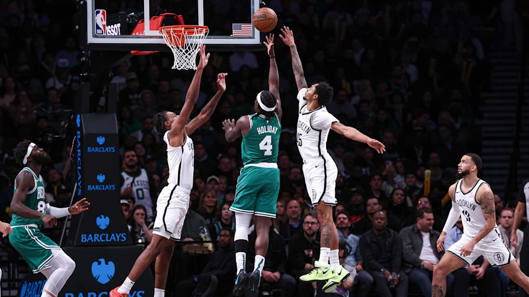 Nov 13, 2024; Brooklyn, New York, USA; Boston Celtics guard Jrue Holiday (4) shoots the ball as Brooklyn Nets guard Keon Johnson (45) and forward Noah Clowney (21) defend during the second half at Barclays Center. Mandatory Credit: Vincent Carchietta-Imagn Images