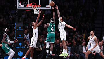 Nov 13, 2024; Brooklyn, New York, USA; Boston Celtics guard Jrue Holiday (4) shoots the ball as Brooklyn Nets guard Keon Johnson (45) and forward Noah Clowney (21) defend during the second half at Barclays Center. Mandatory Credit: Vincent Carchietta-Imagn Images