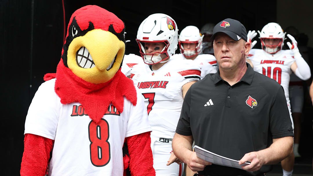 Sep 27, 2025; Pittsburgh, Pennsylvania, USA;  Louisville Cardinals head coach Jeff Brohm (right) leads the team onto the field to play the Pittsburgh Panthers at Acrisure Stadium. Mandatory Credit: Charles LeClaire-Imagn Images