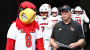 Sep 27, 2025; Pittsburgh, Pennsylvania, USA;  Louisville Cardinals head coach Jeff Brohm (right) leads the team onto the field to play the Pittsburgh Panthers at Acrisure Stadium. Mandatory Credit: Charles LeClaire-Imagn Images