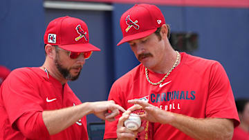 Feb 12, 2025; Jupiter, FL, USA;  St. Louis Cardinals St. Louis Cardinals pitcher Miles Mikolas, right, goes over his grip with pitching coach Dusty Blake during Spring Training. Mandatory Credit: Jim Rassol-Imagn Images