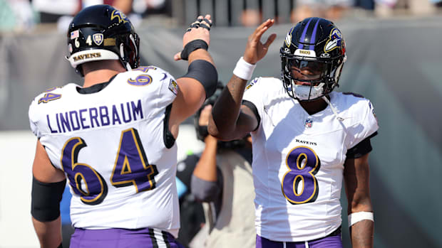 Ravens center Tyler Linderbaum (purple and white uniform) greets quarterback Lamar Jackson after a big play.