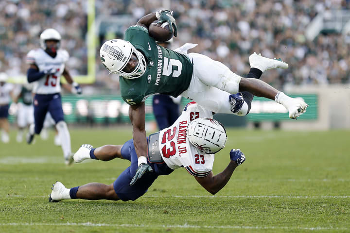 EAST LANSING, MICHIGAN - SEPTEMBER 09: Angelo Rankin Jr. #23 of the Richmond Spiders tackles Nathan Carter #5 of the Michigan State Spartans in the third quarter of a game at Spartan Stadium on September 09, 2023 in East Lansing, Michigan. 