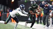 Dec 1, 2024; East Rutherford, New Jersey, USA; New York Jets wide receiver Davante Adams (17) is tackled by Seattle Seahawks cornerback Riq Woolen (27) during the second half at MetLife Stadium. Mandatory Credit: Vincent Carchietta-Imagn Images