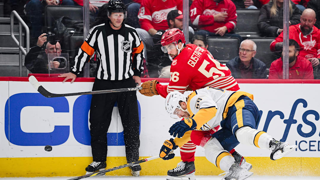 Nov 26, 2025; Detroit, Michigan, USA; Detroit Red Wings defenseman Erik Gustafsson (56) and Nashville Predators left wing Michael Bunting (58) battle for the puck during the first period at Little Caesars Arena.
