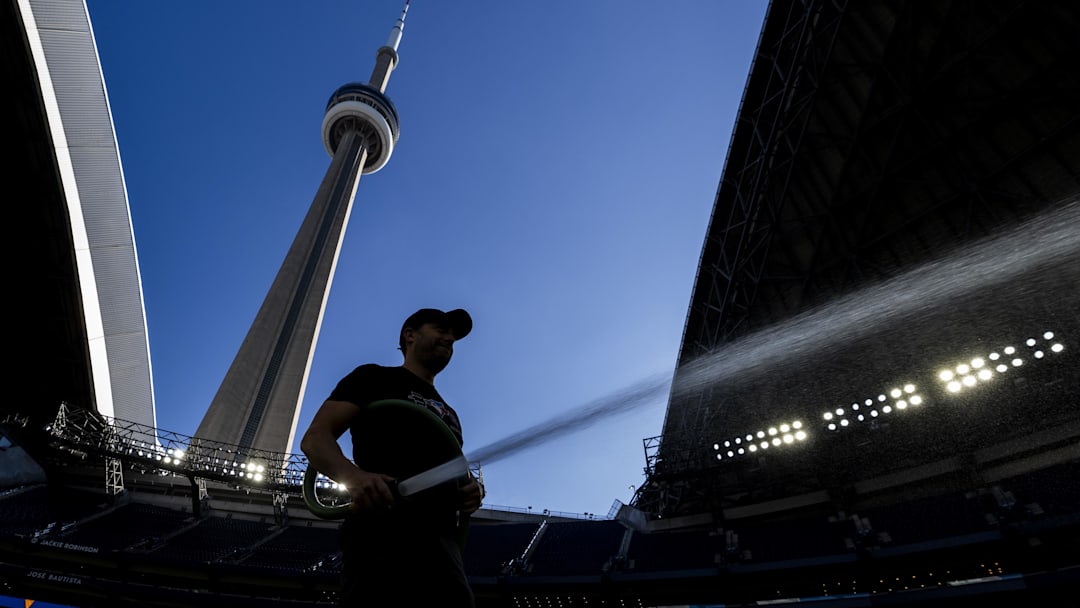 Aug 31, 2025; Toronto, Ontario, CAN; The Rogers Centre grounds crew member waters the field under the CN Tower before an MLB game between the Milwaukee Brewers and the Toronto Blue Jays at Rogers Centre.