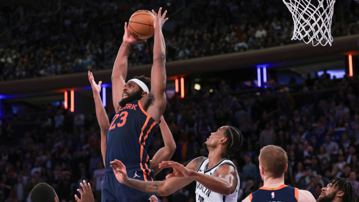 Apr 12, 2024; New York, New York, USA; New York Knicks center Mitchell Robinson (23) rebounds in front of Brooklyn Nets guard Lonnie Walker IV (8) and center Nic Claxton (33) during the second half at Madison Square Garden. Mandatory Credit: Vincent Carchietta-USA TODAY Sports