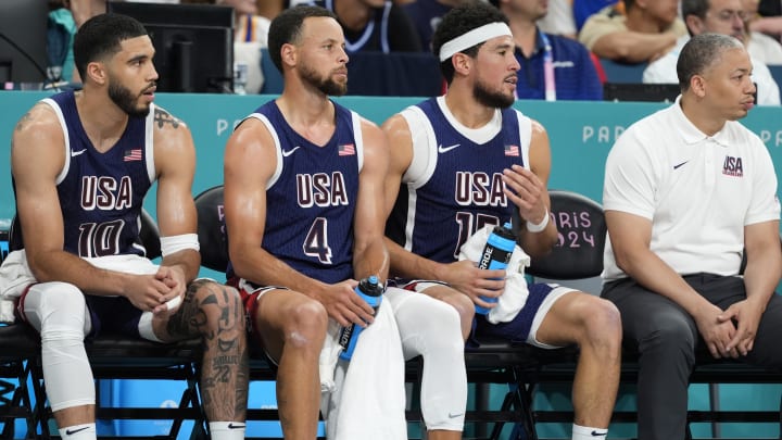 Aug 3, 2024; Villeneuve-d'Ascq, France; United States small forward Jayson Tatum (10), shooting guard Stephen Curry (4), guard Devin Booker (15) and assistant coach Tyronn Lue on the bench in the third quarter against Puerto Rico during the Paris 2024 Olympic Summer Games at Stade Pierre-Mauroy. Mandatory Credit: John David Mercer-USA TODAY Sports