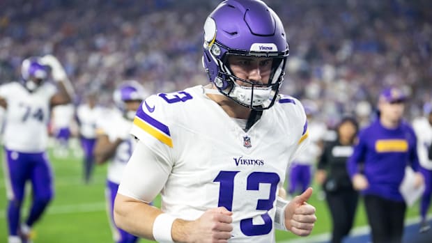 Vikings quarterback Daniel Jones (white jersey, purple helmet) runs off the field after a game.