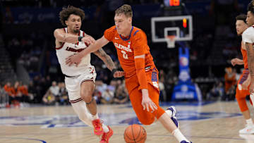 Mar 14, 2025; Charlotte, NC, USA; Clemson Tigers center Viktor Lakhin (0) drives to the basket against Louisville Cardinals guard J'Vonne Hadley (1)  during the first half at Spectrum Center. Mandatory Credit: Jim Dedmon-Imagn Images