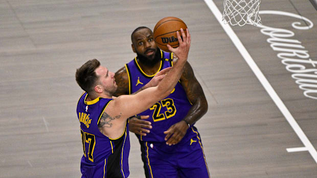 Apr 9, 2025; Dallas, Texas, USA; Los Angeles Lakers guard Luka Doncic (77) makes a layup past forward LeBron James (23) durin