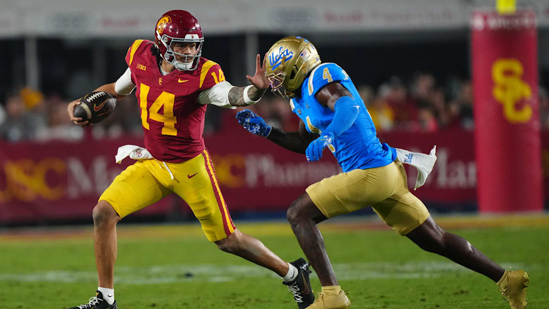 Nov 29, 2025; Los Angeles, California, USA; Southern California Trojans quarterback Jayden Maiava (14) carries the ball against UCLA Bruins defensive back Key Lawrence (4) in the second half at United Airlines Field at Los Angeles Memorial Coliseum. Mandatory Credit: Kirby Lee-Imagn Images