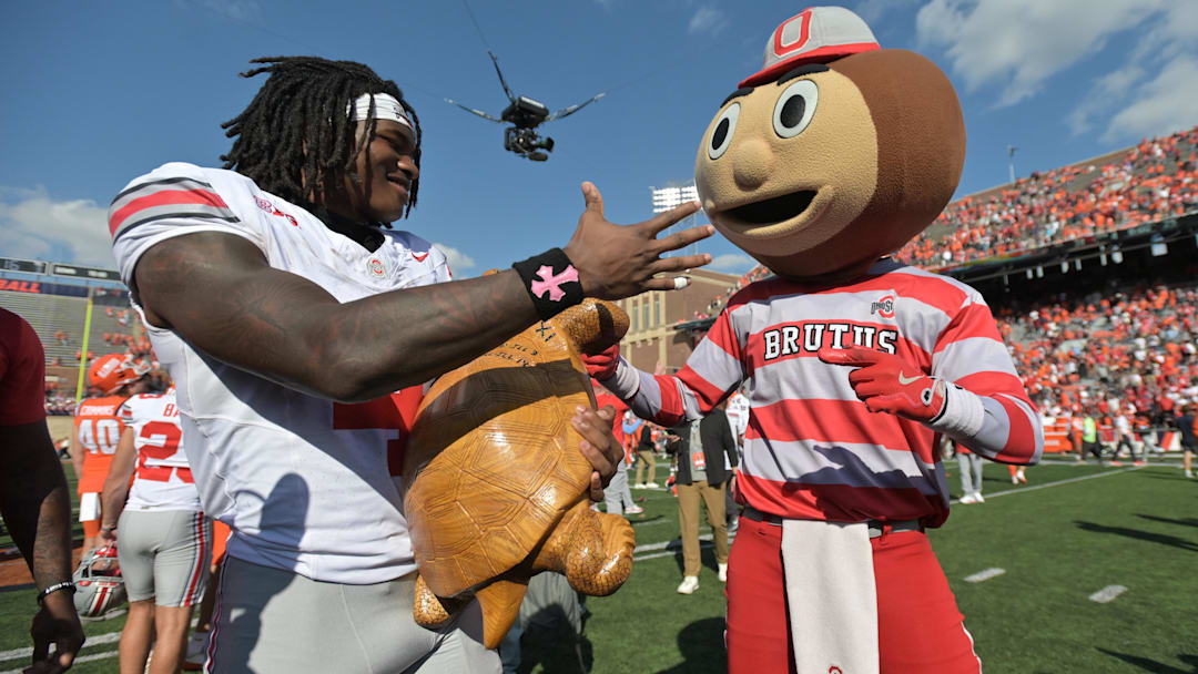 Oct 11, 2025; Champaign, Illinois, USA; Ohio State Buckeyes wide receiver Jeremiah Smith (4) celebrates winning the Illinibuck Trophy with Ohio State Buckeyes mascot Brutus following a win over the Illinois Fighting Illini at Memorial Stadium. Mandatory Credit: Ron Johnson-Imagn Images