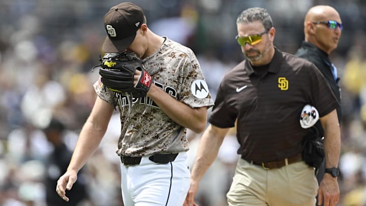 Nick Pivetta (27), left, leaves the field with a trainer during the fourth inning against the Colorado Rockies at Petco Park.