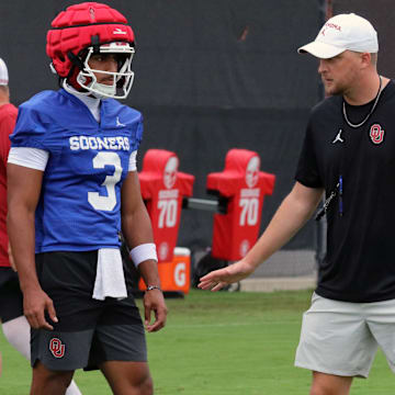 Oklahoma offensive coordinator Ben Arbuckle works with quarterback Michael Hawkins Jr. at practice.