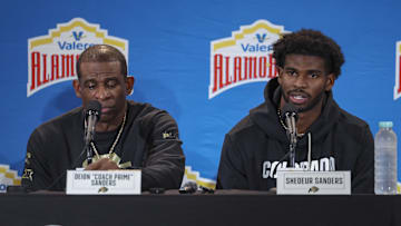 Dec 28, 2024; San Antonio, TX, USA; Colorado Buffaloes head coach Deion Sanders and quarterback Shedeur Sanders (2) talk with the media after the game against the Brigham Young Cougars at Alamodome. Mandatory Credit: Troy Taormina-Imagn Images