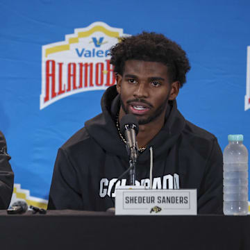 Dec 28, 2024; San Antonio, TX, USA; Colorado Buffaloes head coach Deion Sanders and quarterback Shedeur Sanders (2) talk with the media after the game against the Brigham Young Cougars at Alamodome. Mandatory Credit: Troy Taormina-Imagn Images