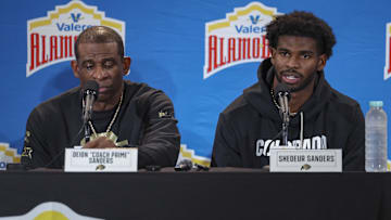 Dec 28, 2024; San Antonio, TX, USA; Colorado Buffaloes head coach Deion Sanders and quarterback Shedeur Sanders (2) talk with the media after the game against the Brigham Young Cougars at Alamodome. Mandatory Credit: Troy Taormina-Imagn Images