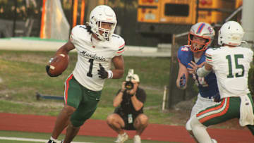 Mandarin wide receiver Brysen Wright (1), with help from blocking quarterback Knox Annis (15), tries to escape from Bolles defensive end Asher Ghioto (34) after returning into his own backfield on his way to a 77-yard touchdown reception during a high school spring football game on May 22, 2025.