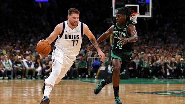 Dallas Mavericks guard Luka Doncic (77) dribbles the ball against Boston Celtics guard Jrue Holiday.