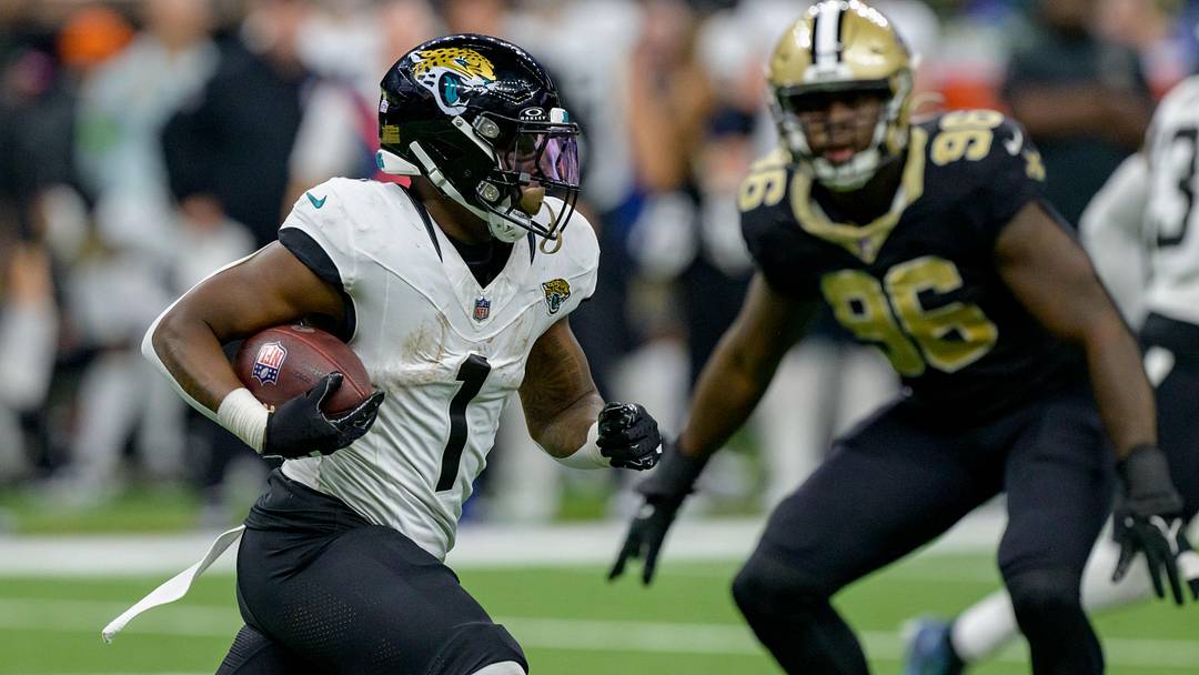 Oct. 19, 2023; New Orleans, Louisiana, USA; Jacksonville Jaguars running back Travis Etienne Jr. (1) runs against New Orleans Saints defensive end Carl Granderson (96) during the third quarter at the Caesars Superdome. Mandatory Credit: Matthew Hinton-Imagn Images