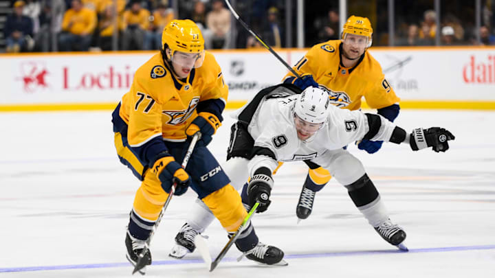 Nov 4, 2024; Nashville, Tennessee, USA;  Nashville Predators right wing Luke Evangelista (77) and Los Angeles Kings right wing Adrian Kempe (9) fight for the puck during the third period at Bridgestone Arena. Mandatory Credit: Steve Roberts-Imagn Images