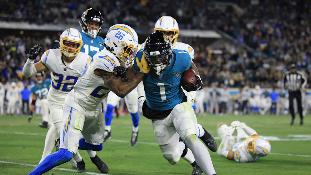Jacksonville Jaguars running back Travis Etienne Jr. (1) rushes for yards against Los Angeles Chargers cornerback Asante Samuel Jr. (26) during the third quarter of an NFL first round playoff football matchup Saturday, Jan. 14, 2023 at TIAA Bank Field in Jacksonville, Fla. Jacksonville Jaguars edged the Los Angeles Chargers on a field goal 31-30. [Corey Perrine/Florida Times-Union]

Jki 011423 Chargers Jags C 54